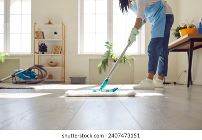 Professional cleaner mopping a bright tiled floor in a sunlit room